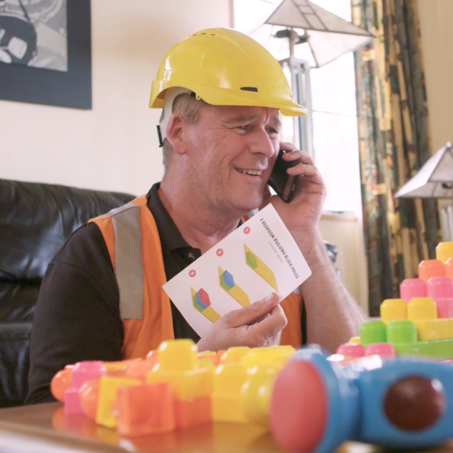 A builder wearing hard hat talks on the phone.